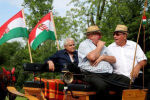 Rózsa Sándor Fesztiválon magyar zászlókkal díszített szekéren ülő férfiak beszélgetése